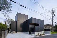 シンプルでモダンな黒の外観が魅力的な住宅。シンメトリーなデザインが周囲の風景に溶け込み、洗練された印象を与える。【iDpluss アイディープラス】