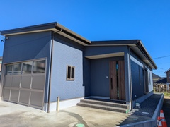 シンプルでモダンなデザインの住宅外観。青い外壁とシャープなラインが印象的な平屋建てが、周囲の風景と調和している。【大栄ホーム】