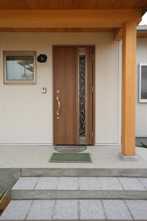 木目調のドアを持つシンプルで温かみのある玄関。ステップが付いており、出入りがしやすく設計されている。