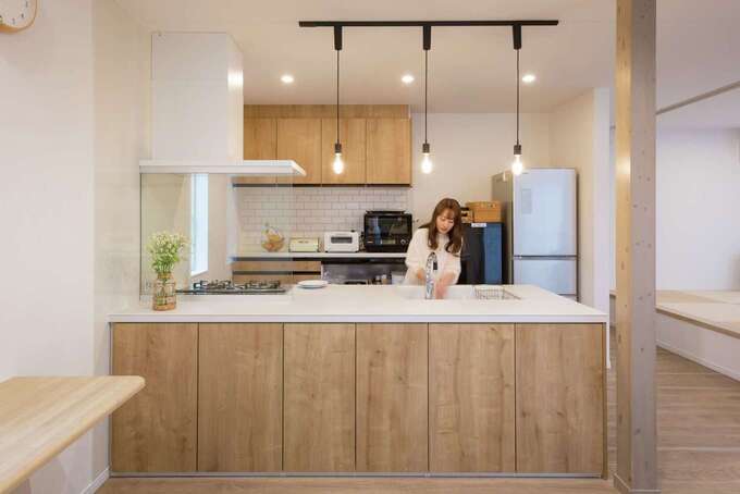 白ベースに木の優しい色合いがマッチしたキッチン。照明や設備のチョイスもハイセンスで、まるでモデルルームのようにオシャレ