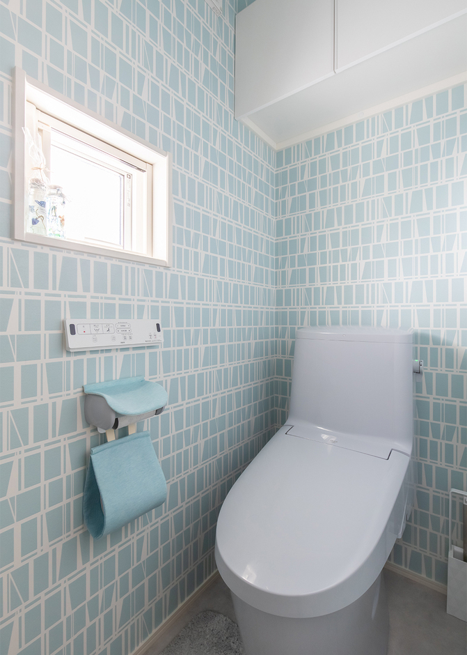 トイレには清潔感のある水色の壁紙をセレクト。収納力のある吊り戸棚も設けた