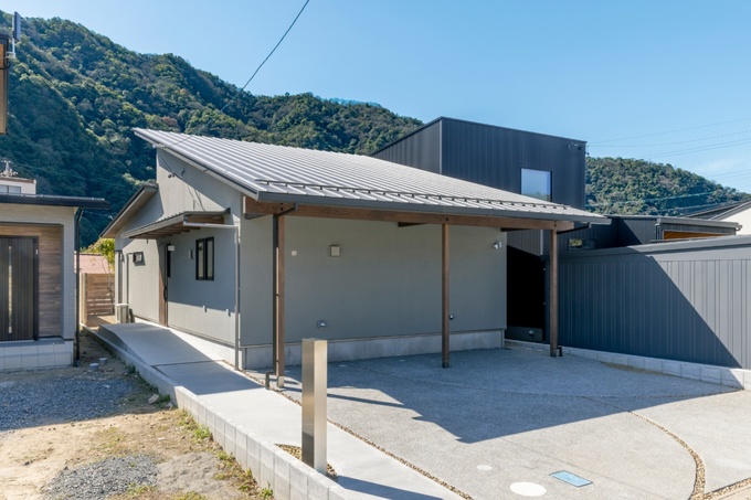 美しい山々を背景にしたシンプルな平屋の外観。モダンなスタイルが落ち着いた雰囲気を醸し出し、周囲の自然環境と調和している。