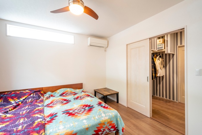 寝室にはカラフルなデザインのベッドカバーが映える。シンプルな内装と機能的なクローゼットが特徴。