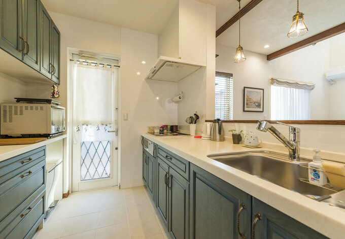 オリーブグリーンの収納扉がハイセンスなペニンシュラキッチン。タイルの床はお手入れがしやすい