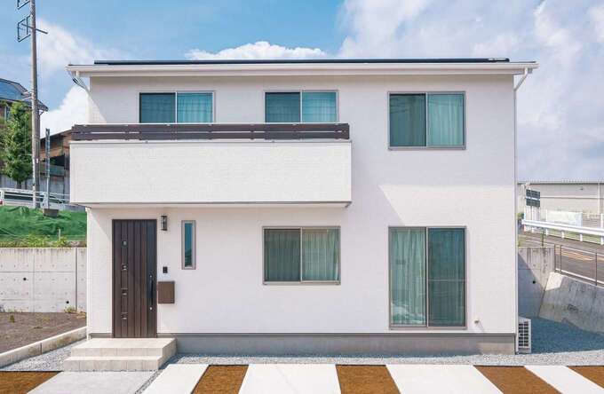 総2階建てのすっきりした外観。バルコニーの柵とドアのダークブラウンを白い外壁の差し色に