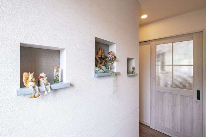 リビングに繋がるドアにはチェッカーガラスを使用。ガラスや格子は数種類から選ぶことで、自分らしさを表現できる。玄関正面の壁にはニッチを造作。雑貨などを飾って楽しめる
