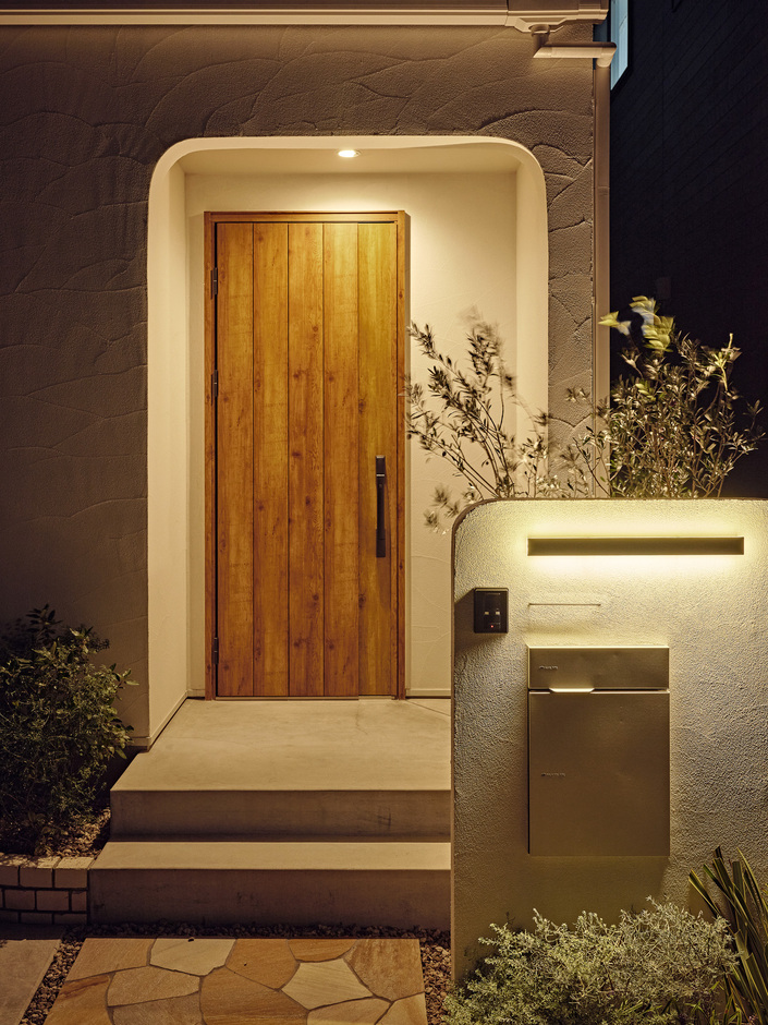 灯りが木製のドアを引き立てる玄関ポーチ