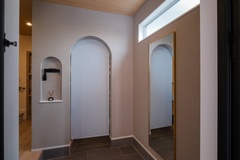 広々とした玄関ホール。ロールスクリーンで隠したアーチ状の入口の向こうはシューズクロークになっている。