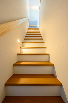 スタイリッシュな木製の階段。壁に沿った照明が階段全体を優しく照らし、安全で洗練された雰囲気を醸し出す。