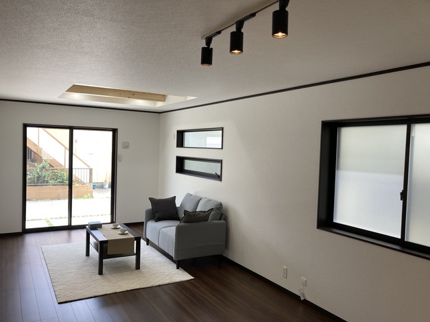 シンプルで落ち着いた雰囲気のリビングスペース。照明と窓が自然光を差し込み、心地よい空間を演出している。