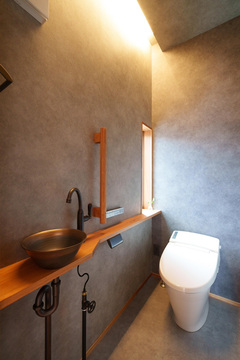 グレージュのクロスを貼ってシックな雰囲気に仕上げたゲスト用のトイレ。平屋でもトイレを2か所に設置することで、渋滞を緩和することができる