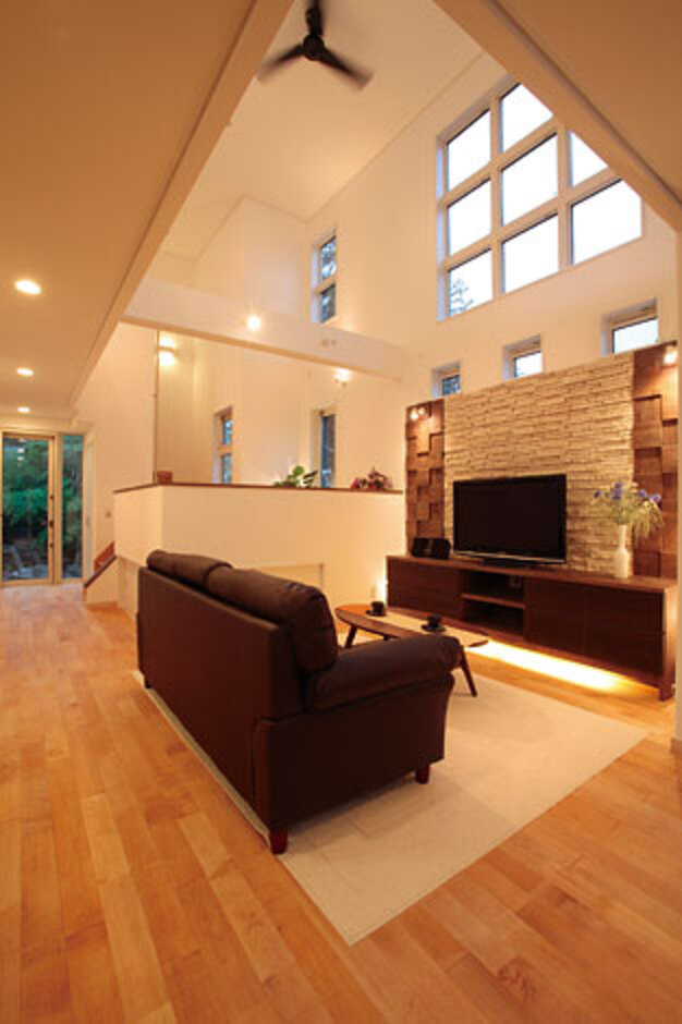 石貼りのテレビステーションが家族の団らんに上質なくつろぎを添える。9連の窓からは明るさと周囲の木々の緑。通り側を閉じることで、プライベート感が守られている