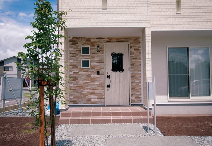 外壁は白を基調にベランダ部分と玄関回りに変化をつけた。ドアは室 内のデザインと合わせたアンティーク風