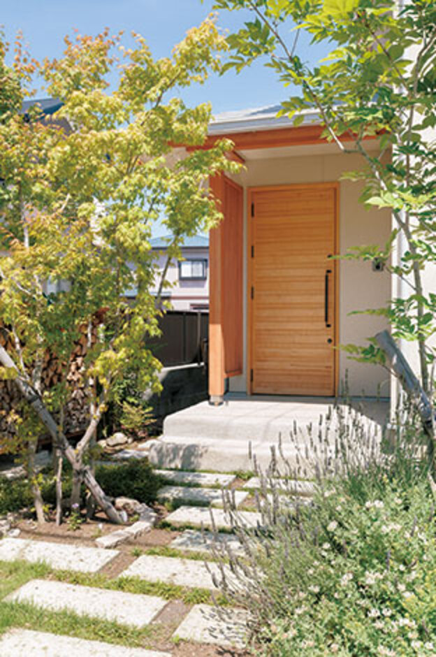 緑の小径を抜けて玄関へ。ファサードの敷石は耐火性にすぐれた大谷石。職人の手刻みで造った重厚な玄関扉はサクラ材を使用