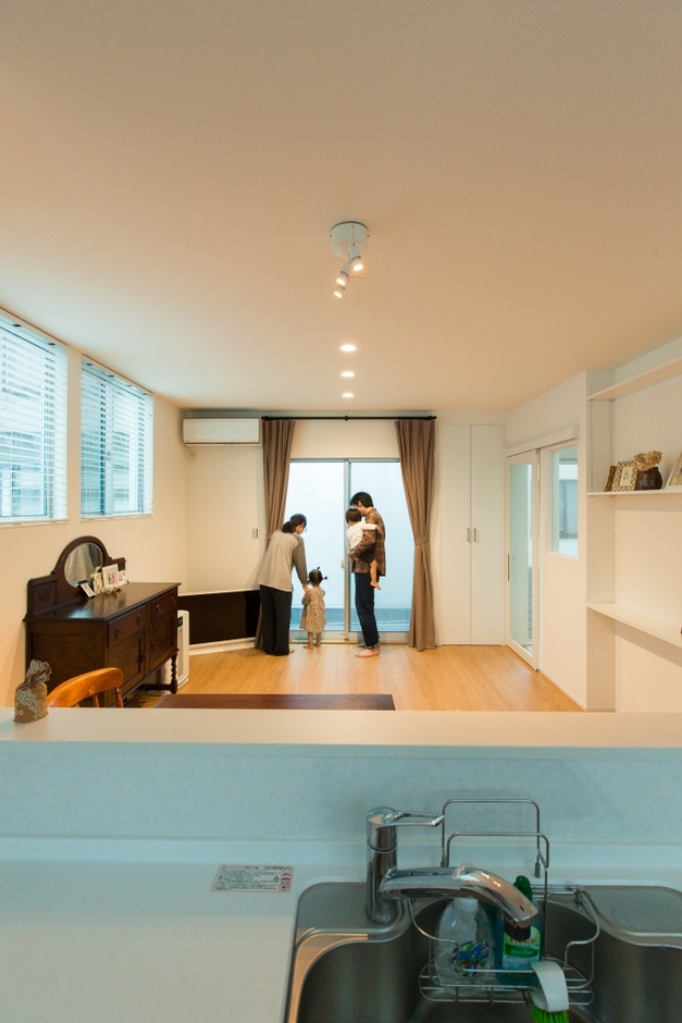 日光をたっぷり取り込んだ明るいリビング。周りの建物の位置に合わせて窓の高さも調整した。入口のドアも全面ガラスで採光と空間演出の工夫