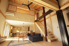 勾配屋根の吹き抜けが開放的なLDK。黒く塗られた8寸（24cm）の大黒柱と、その奥にある赤色の8角形の柱は、生漆（きうるし）に顔料を混ぜ、何度も塗りと拭き取りを繰り返し仕上げたこの家のシンボル的存在