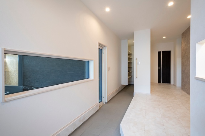 モダンなデザインの玄関ホール。長い廊下と大きな窓が特徴で、開放感を演出している。