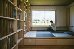 書斎＆寝室にしつらえた壁一面の書棚には、趣味の本や建築関係の本がずらりと並ぶ。窓際にはカウンターを設けてあり、外の田園風景を見ながらゆっくり読書を楽しむことも【水田建設】