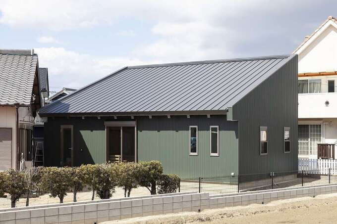 実家の敷地内に建てたK邸。日照と風向きのシミュレーションを実施して建物を配置した。外壁は夫婦の好きなモスグリーンのガルバリウムを採用。大胆な片流れの屋根が印象的