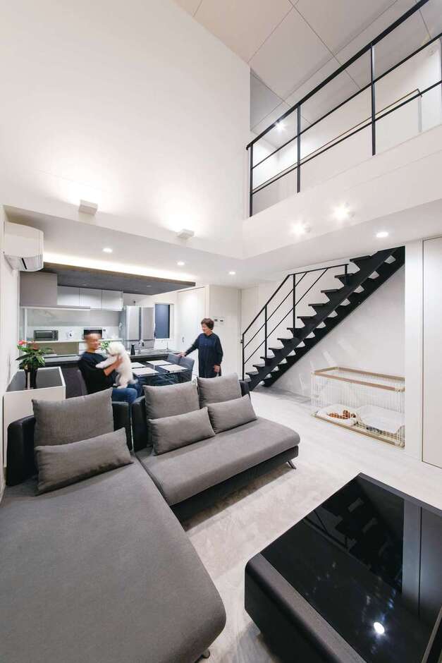 壁と床を白で統一し、アイアンのスケルトン階段や手すりの黒を利かせたリビング。開放感あふれる吹抜け空間に、スポットライトや間接照明による灯りの演出が映える