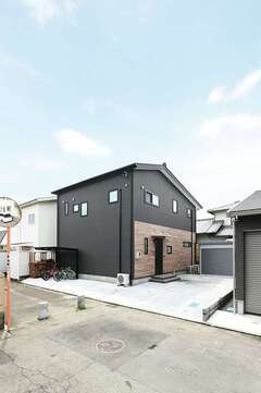 黒と木調のサイディングがかっこいい外観。道路側は開口部を最小限にして、プライバシーに配慮したつくりに。ストーブ用の薪ストッカーも完備されている。バイクガレージにはご主人の愛車がスタンバイ