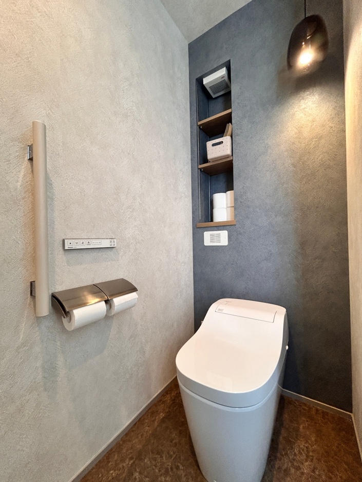 モダンなデザインのトイレ空間。シンプルな壁面に統一感のある棚がおしゃれで、機能性と美しさを兼ね備えた空間