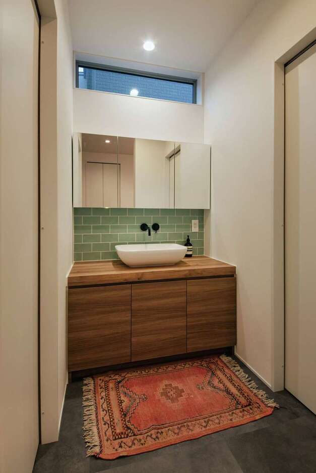 玄関から近い位置にある造作の手洗いコーナー。モスグリーンのタイルが空間に華やぎを与える。左がトイレ、右が脱衣室と浴室