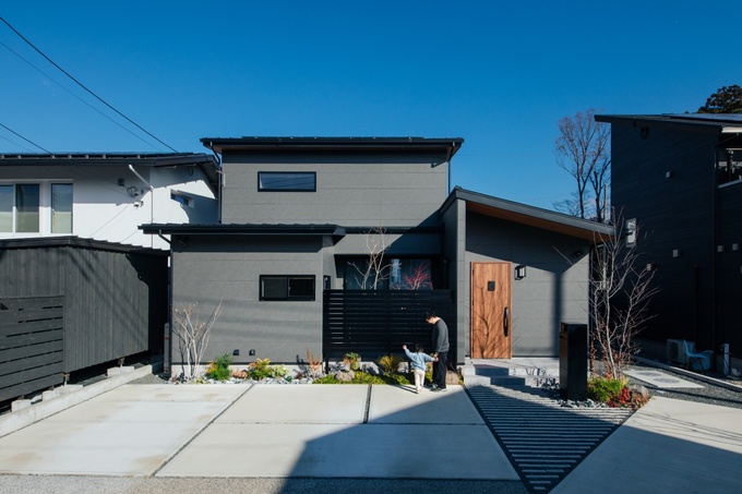 モダンなデザインの住宅外観。片流れ屋根が特徴で、クリーンなラインと落ち着いた色合いが調和している。駐車スペースも広々と確保されている。