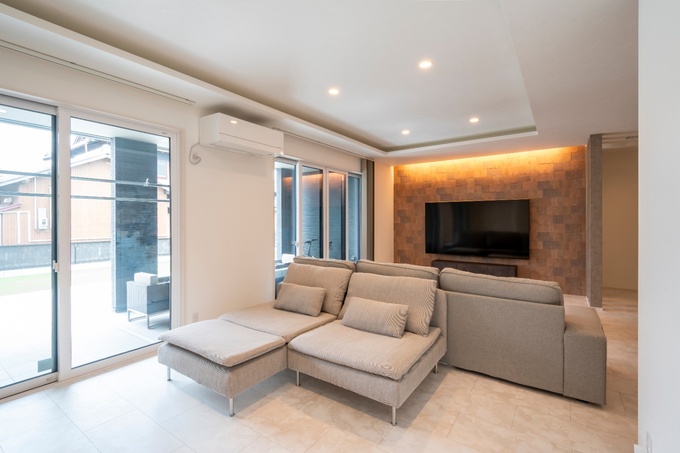 リビングには大きな窓があり、明るい光が差し込む。スタイリッシュなソファが配置され、寛ぎの空間を演出。