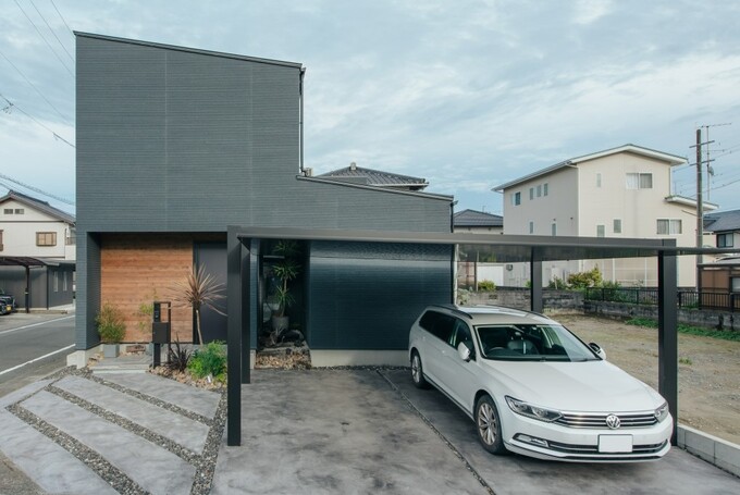 グレーのALC外壁にポーチのシダーが調和した外観。スタイリッシュな建物をより引き立てるよう、エクステリア、植栽、カーポートのデザインにもこだわっている