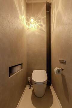 1階のトイレは来客も使うため、トイレットペーパー用のニッチや、奥の壁裏に作った収納スペースなど技あり設計が光る。シンプルながら洗練された印象なのは、あえて壁紙を1色で統一し、照明で景色を作っているから【ハートホーム】