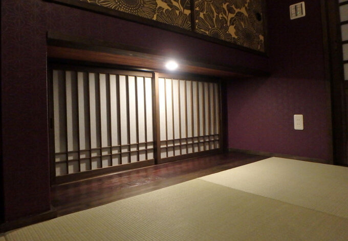 明かりに照らされた木製障子の地窓はダークな印象の和室に光を与え、広がり感をもたらす