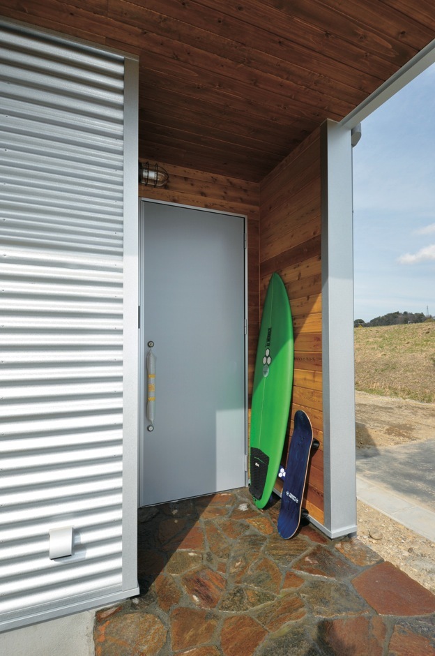 ポーチまわりは木を張ってアクセントとした。サーフボー ドがよく似合う