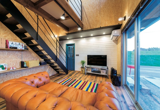 スケルトン階段と2階の廊下がダイナミックに吹き抜けを渡る。階段下は可動棚のディスプレイスペースに