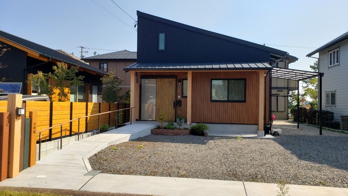 片流れ屋根が特徴的なシンプルモダンの外観デザイン。ウッドの外壁と黒い屋根のコントラストが洗練されており、周囲の自然環境に調和する。