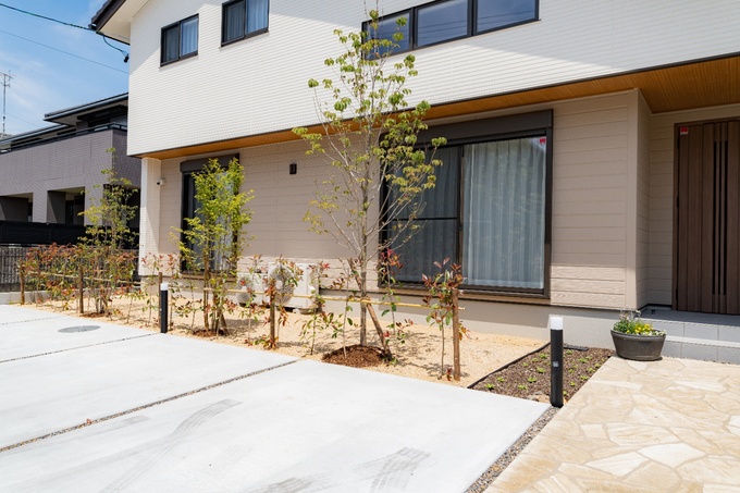 シンプルでモダンなデザインが際立つ住宅の外観。手入れの行き届いた植栽と広々とした駐車スペースが、スタイリッシュな印象を与える。