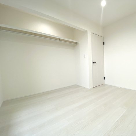 シンプルで広々としたクローゼット。衣類をたくさん収納でき、整理整頓がしやすい設計。白を基調とした明るい空間が特徴。