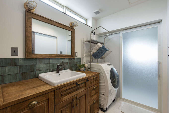 アンティークなデザインの洗面台は、Oさんが気に入ったものを持ち込んで設置。カップボードと同じタイルを貼って統一感を出した。ハイサイドライトから柔らかな光が差し込み、北面でも十分な明るさをキープできる