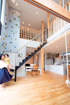 ダイナミックな吹抜けのリビング。子どもたちは2階からロープで1階に降りてくる。天井まで届くボルダリングは、ご主人も筋トレに活用