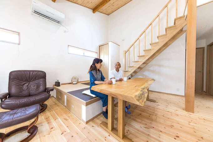 間取りに合わせて造作した一枚板のテーブル。椅子は置かずにスペースを節約。階段は大工の技術を活かしてすべて天然木で製作。最下段は畳の小上がりが兼ねている