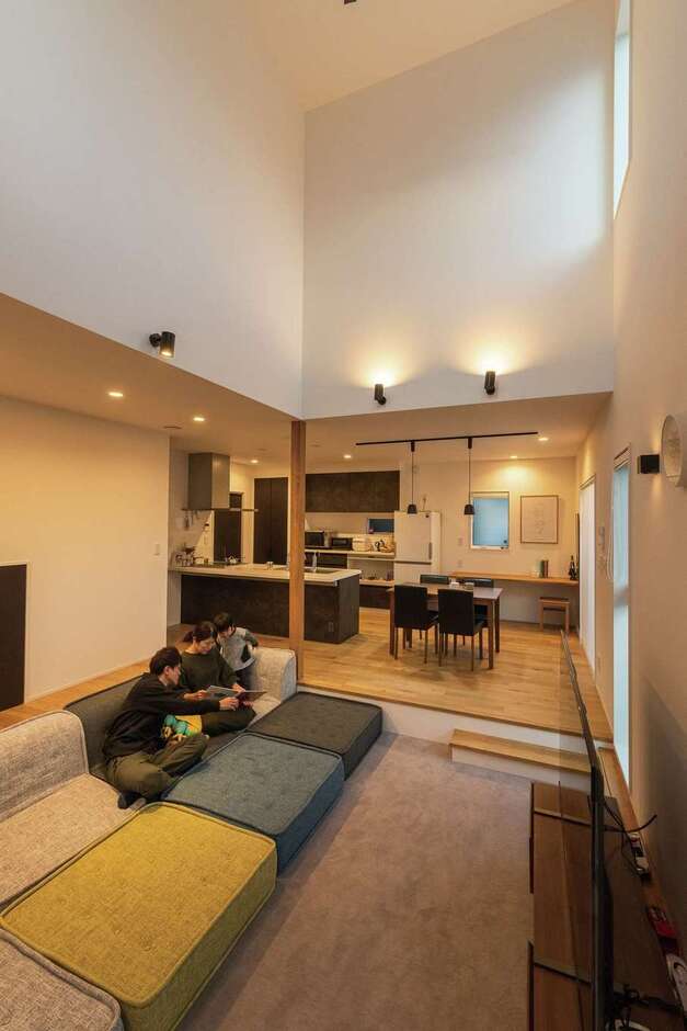 24畳のLDKは、1/4の6畳分を吹抜けにして明るさと開放感を演出。人気インテリアブランドのローソファの寸法に合わせて設計したアンダーリビングは、カーペット敷きのくつろぎ空間。床面が一段下がることで吹抜けがより高く見え、空間の広がりを感じられる