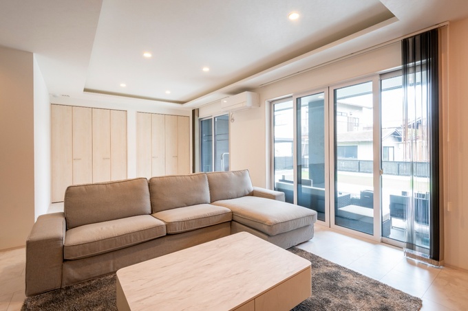 大きな窓から自然光が差し込むリビング。広々としたソファと落ち着いたインテリアが、家族団らんの場を演出する。