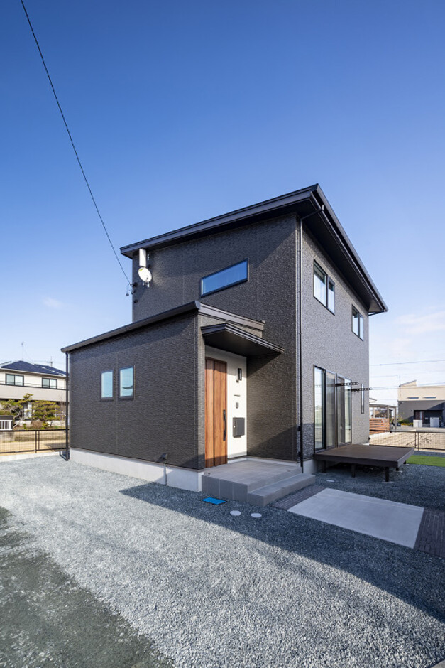モダンな二階建て住宅の外観。シンプルながらもエレガントなデザインが周囲に調和している印象を与える