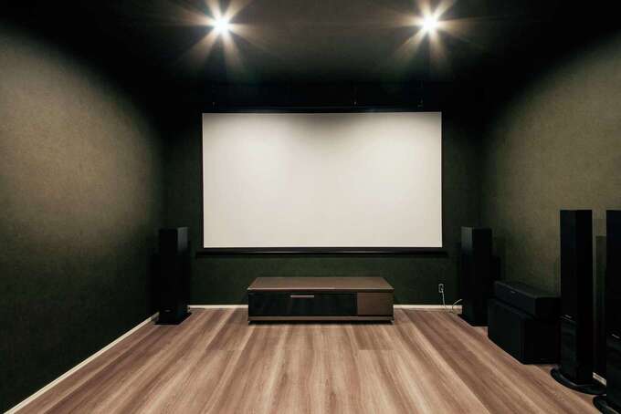 ご主人が最高のサラウンドシステムで趣味のゲームや映画を楽しむシアタールーム。映画館さながらの暗い空間に仕上げた