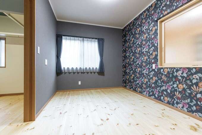 2階の子世帯の主寝室はウォークインクローゼット付き。室内窓を開けると、1階にいる家族の様子がわかる。グレー系ネイビーカラーのクロスと大判の花柄クロス、カーテンの組み合わせが絶妙だ