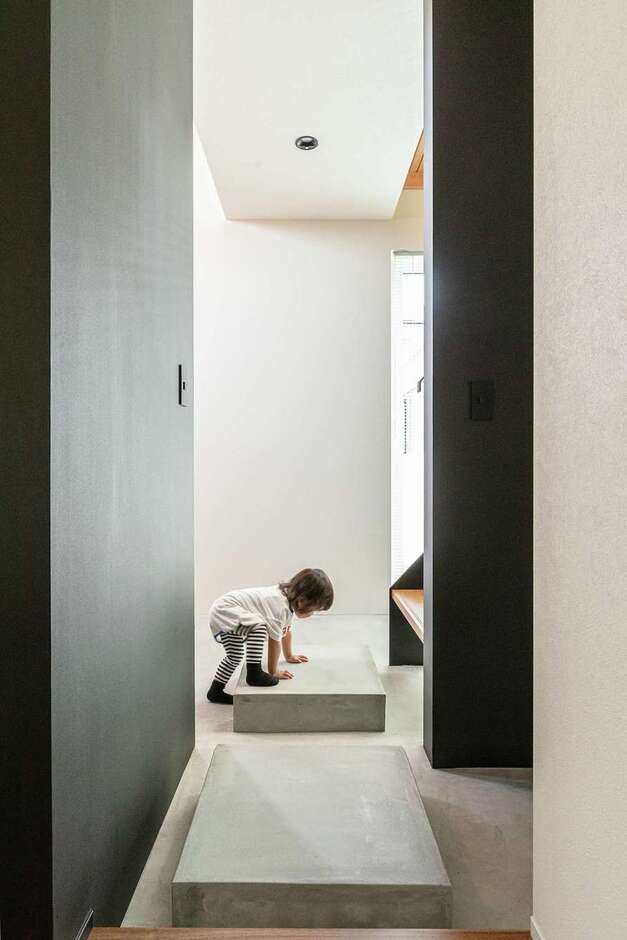 いわゆる玄関ホールはなし。モルタルの飛び石を設けて階段とシューズクローク、1階フロアをつなぐ動線にした