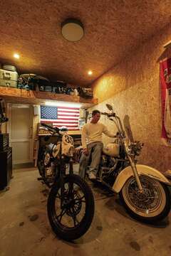 ハーレーとオフロードバイクを格納するビルトインガレージ。OSB合板でワイルドに仕上げ、作業台とロフトも設置した。超アウトドア派のご主人は家にじっとしていられない性格だったのに、憧れの「男の隠れ家」ができたことで、休日は朝からこもってバイクいじりを楽しんでいる【住起産業（アキュラホーム三島中店）】