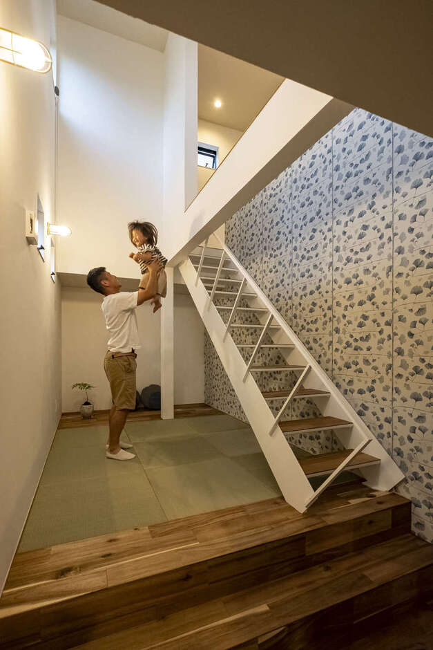 階段下のデッドスペースを活かして作ったスキップフロアの畳コーナー。白く塗装した鉄骨階段と輸入クロスで軽やかな雰囲気に