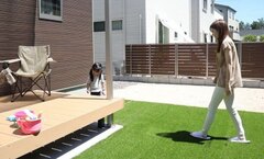 庭で親子が遊ぶ様子。人工芝の上にウッドデッキが延び、家族で outdoor アクティビティを楽しむのに最適な作りである。【ユースタイルハウス　上村建設】
