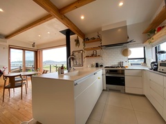 明るく開放的なキッチン。白を基調としたデザインに、木の梁が温かみを加えている。料理をしながら景色を楽しめる窓が魅力的である。